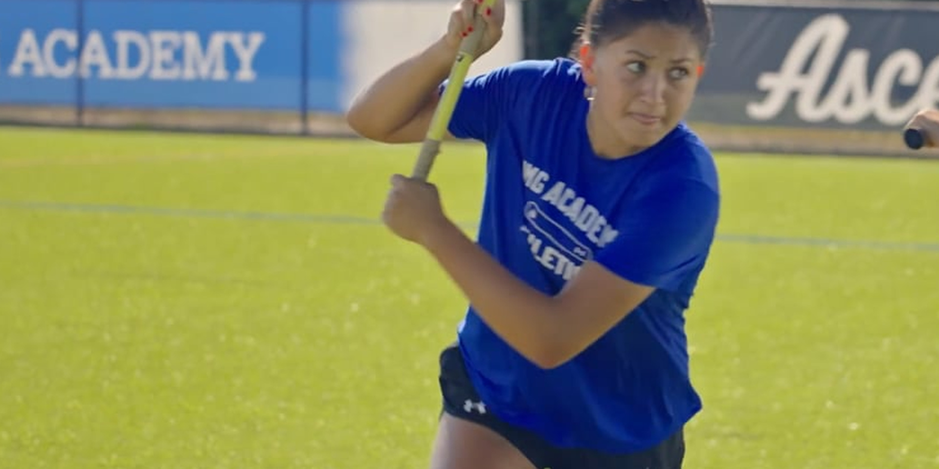 A lacrosse player holds her stick raised during an attacking drill.