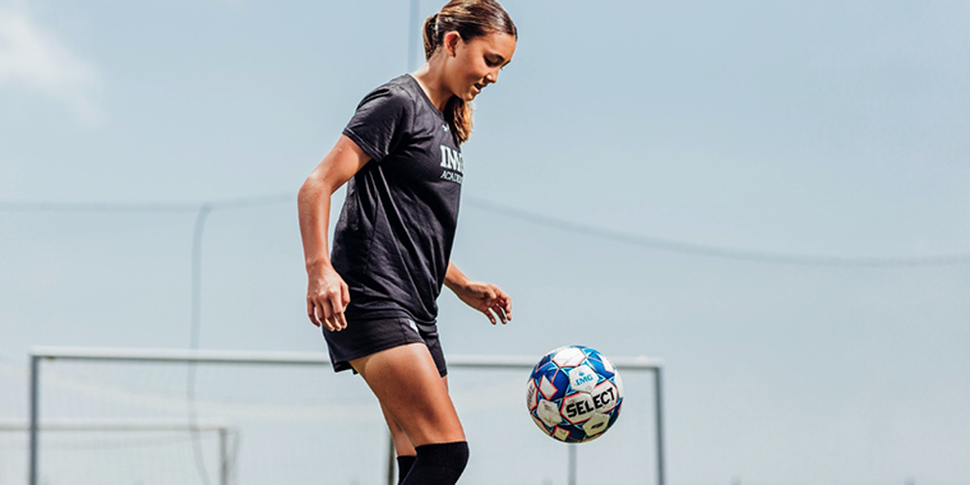 A soccer player controls a ball with her foot.