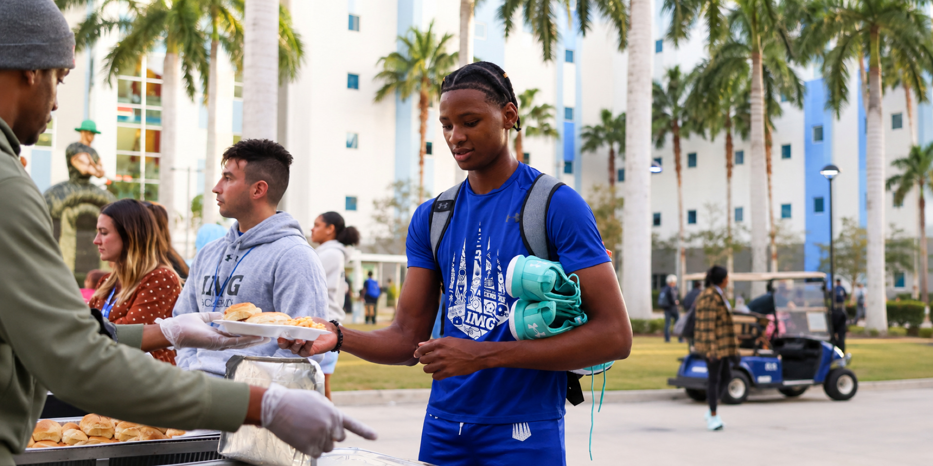 An athlete receives a boxed meal at an outdoor food station.
