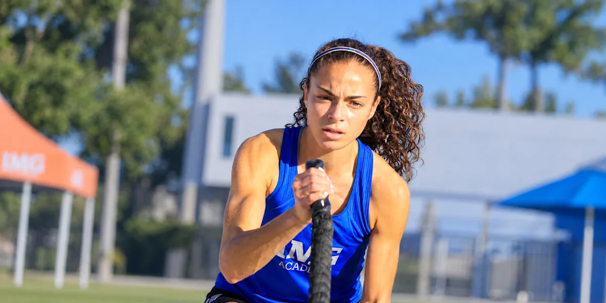 A track athlete runs outdoors in a blue uniform.