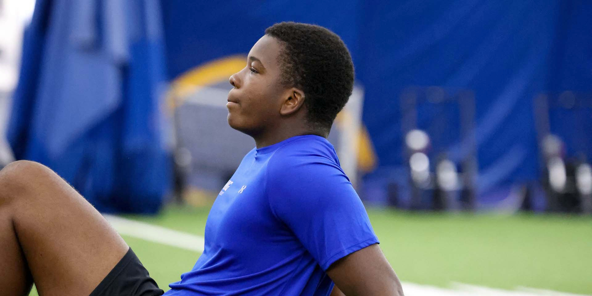 An athlete sits on indoor turf with his eyes closed during a relaxation exercise.