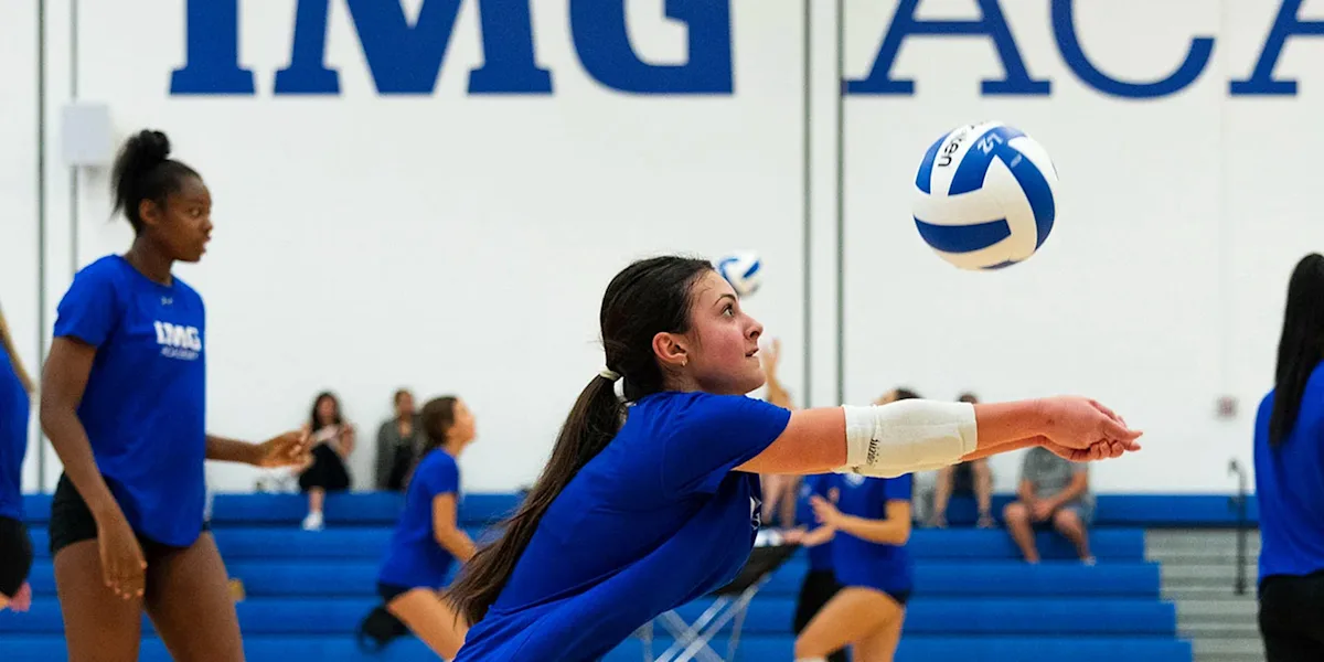 A volleyball player passes a ball with her forearms on an indoor court.