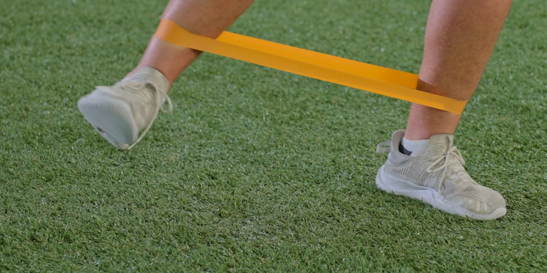 A close view shows an athlete balancing with a resistance band around the ankles.