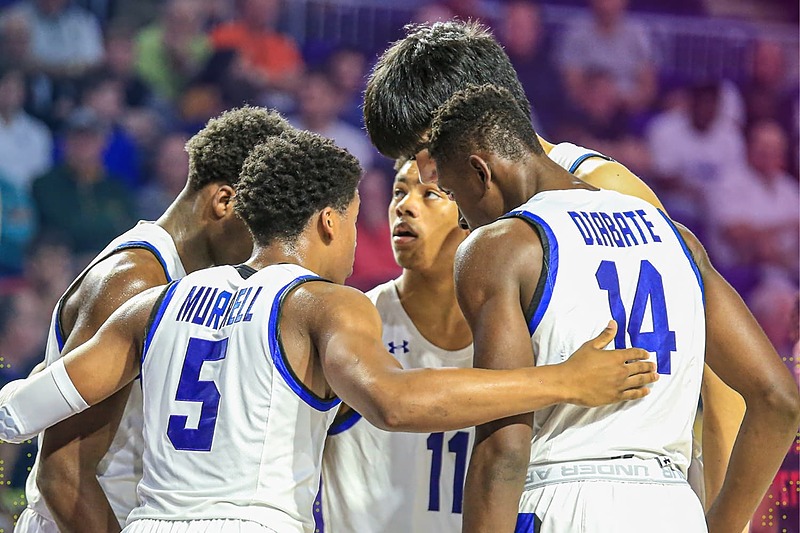 IMG Academy basketball players in a close huddle on the court, communicating strategy and supporting one another during a game.