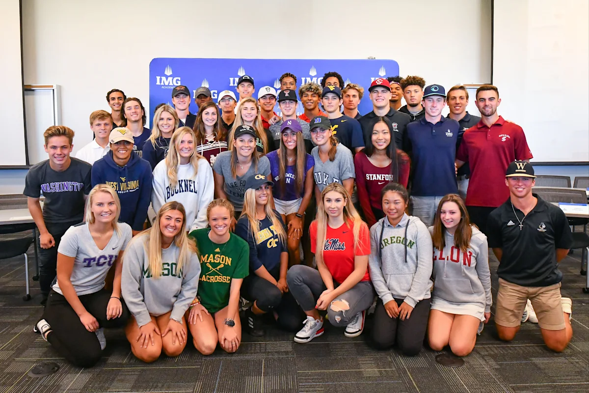 Group of IMG Academy student-athletes wearing college apparel, celebrating their recruitment to various NCAA programs across multiple sports.