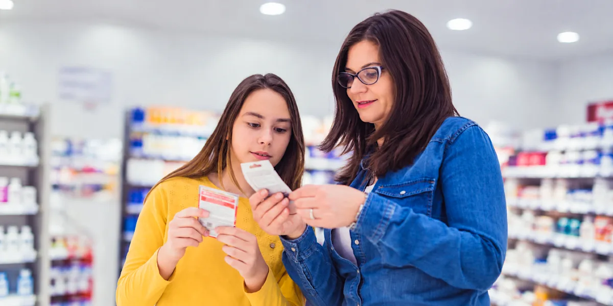 An adult and a young athlete examine a product in a store aisle.