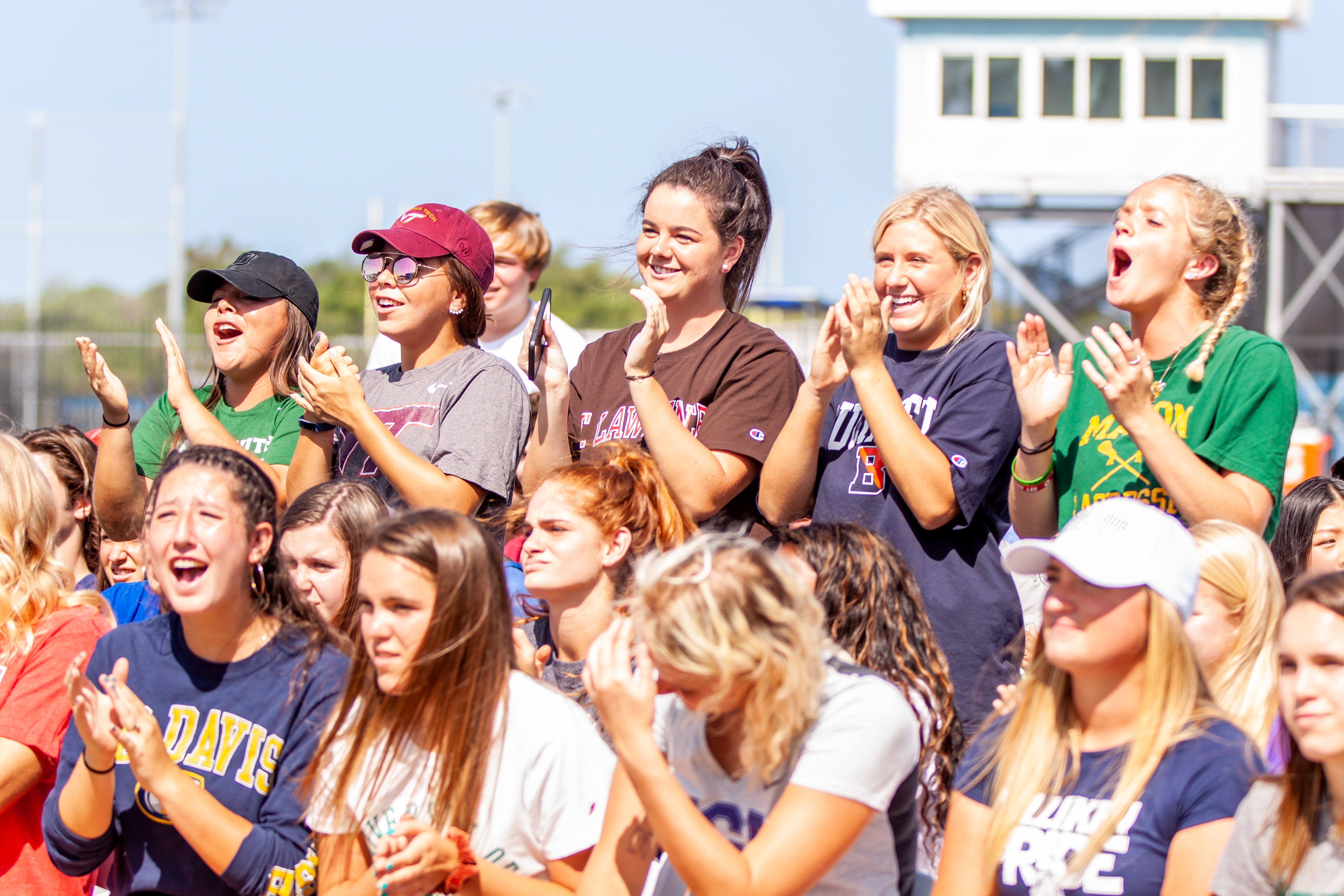 Group of student-athletes enthusiastically cheering and wearing college gear, representing the excitement and strong community often found in junior college athletic programs.