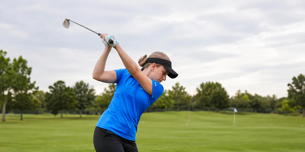 A golfer follows through on a swing on a course.
