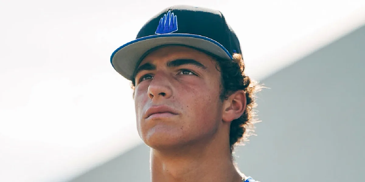 A baseball player wearing a team cap looks into the distance.