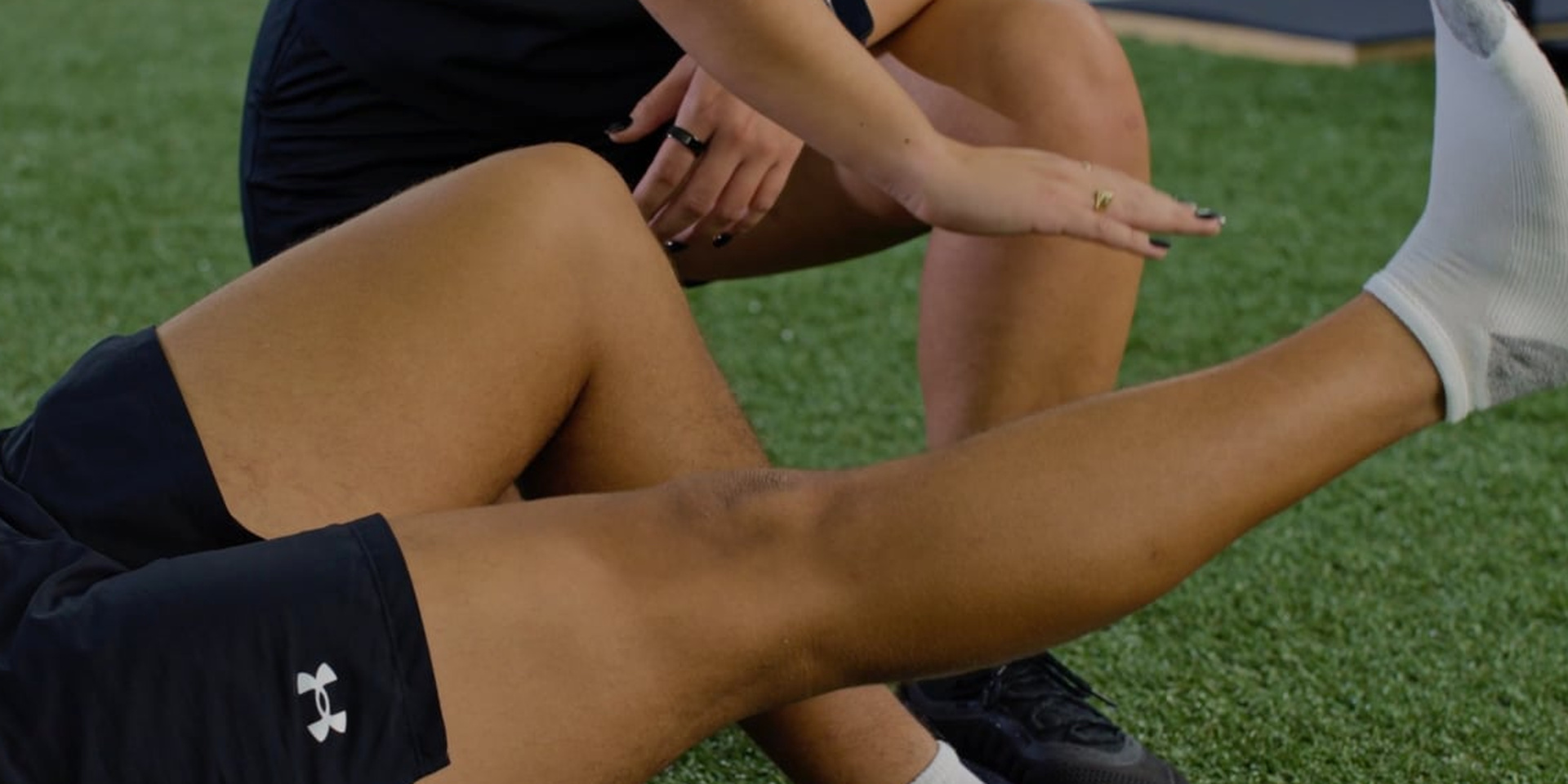An athlete raises one straight leg during a supervised floor exercise.