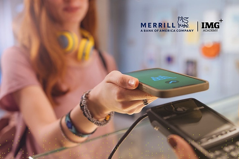 Student using a smartphone to make a contactless payment, with Merrill and IMG Academy logos visible, representing a student guide to managing money and financial literacy.