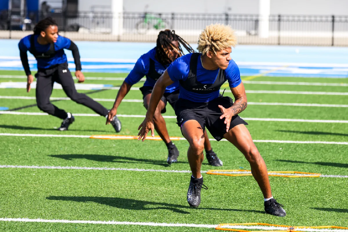 Males on field doing agility drills.