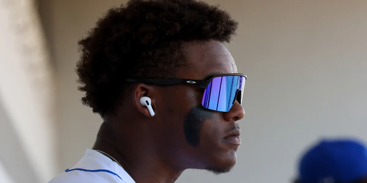 An athlete wearing sunglasses and earbuds looks to the side.