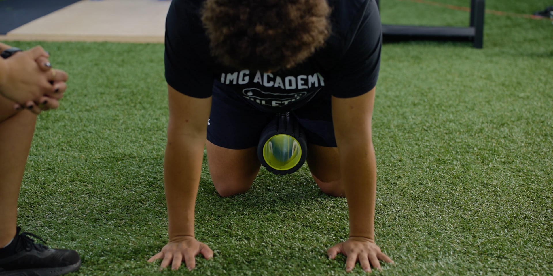 An athlete kneels on all fours with an exercise ball between his knees.