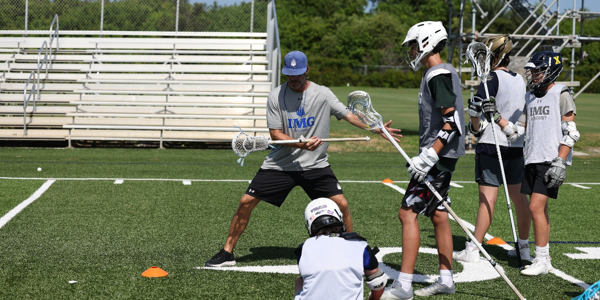 Lacrosse coach demonstrates stick skills to student-athletes during training at IMG Academy.
