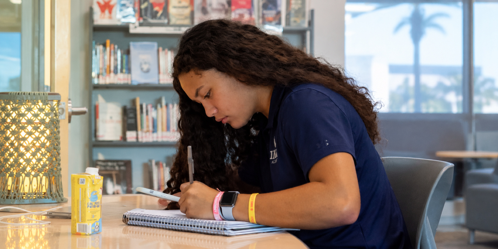 A student writes in a notebook at a table.
