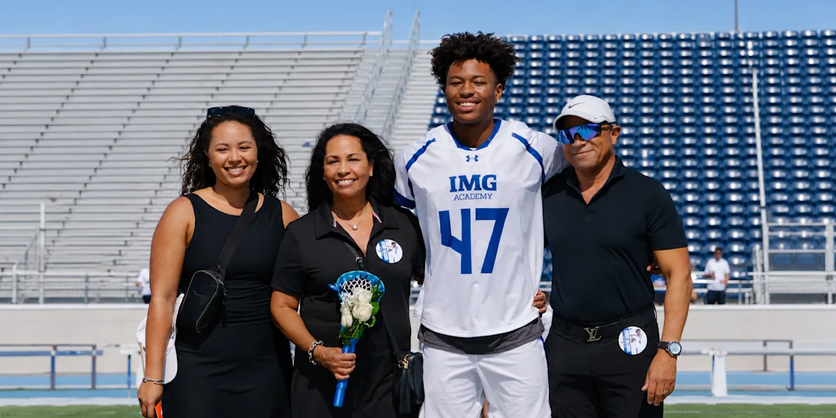 A football player poses with family members in a stadium.