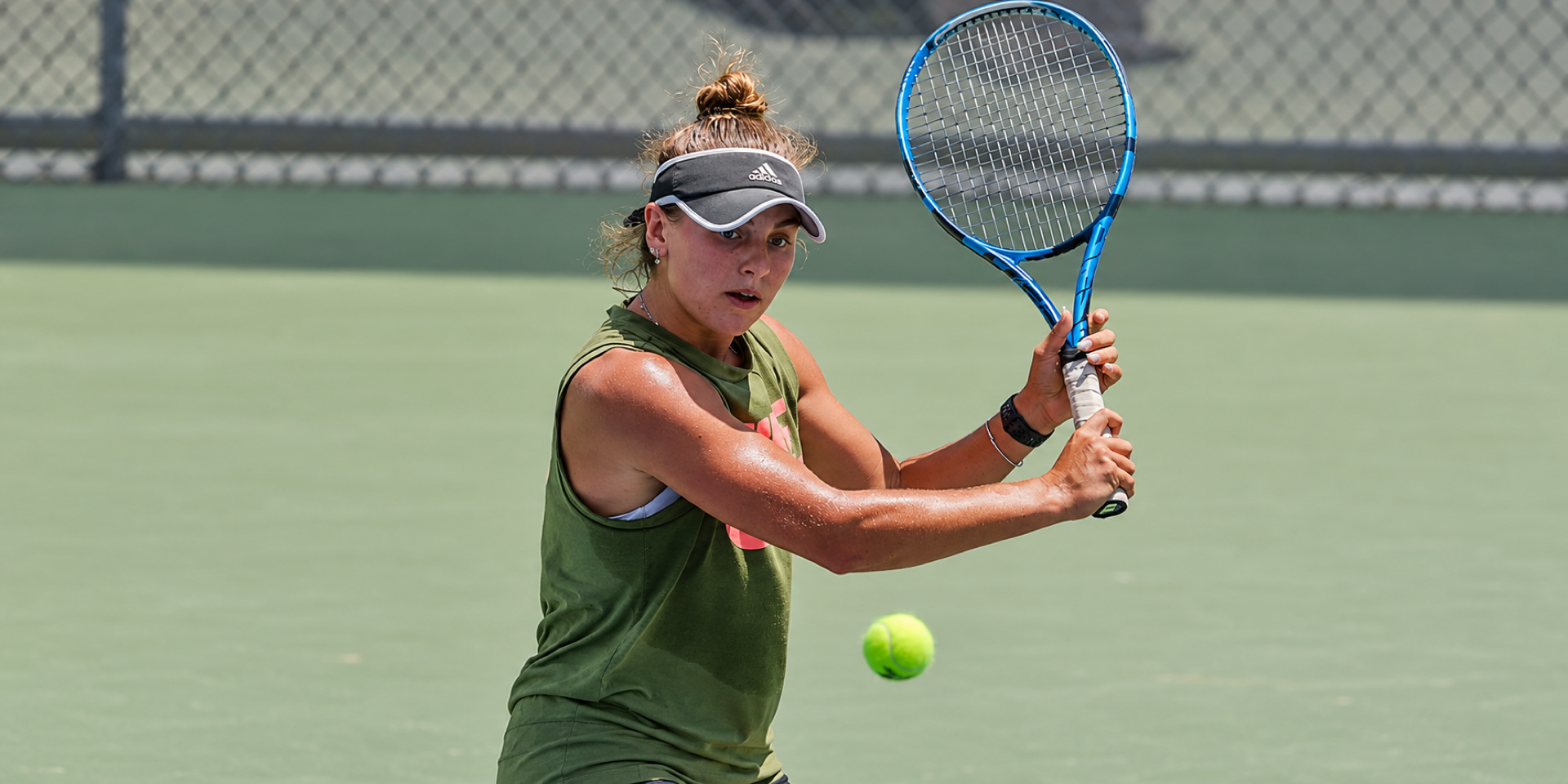 A tennis player prepares a backhand as a ball approaches.