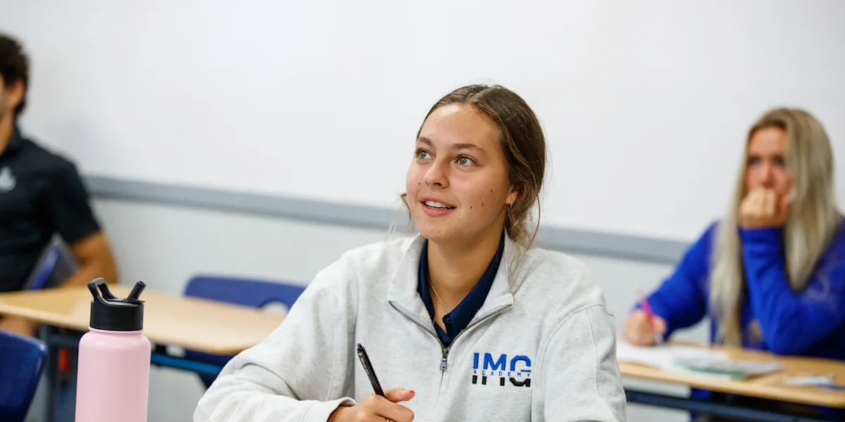 Female high school student-athlete listening to trainer and taking notes.