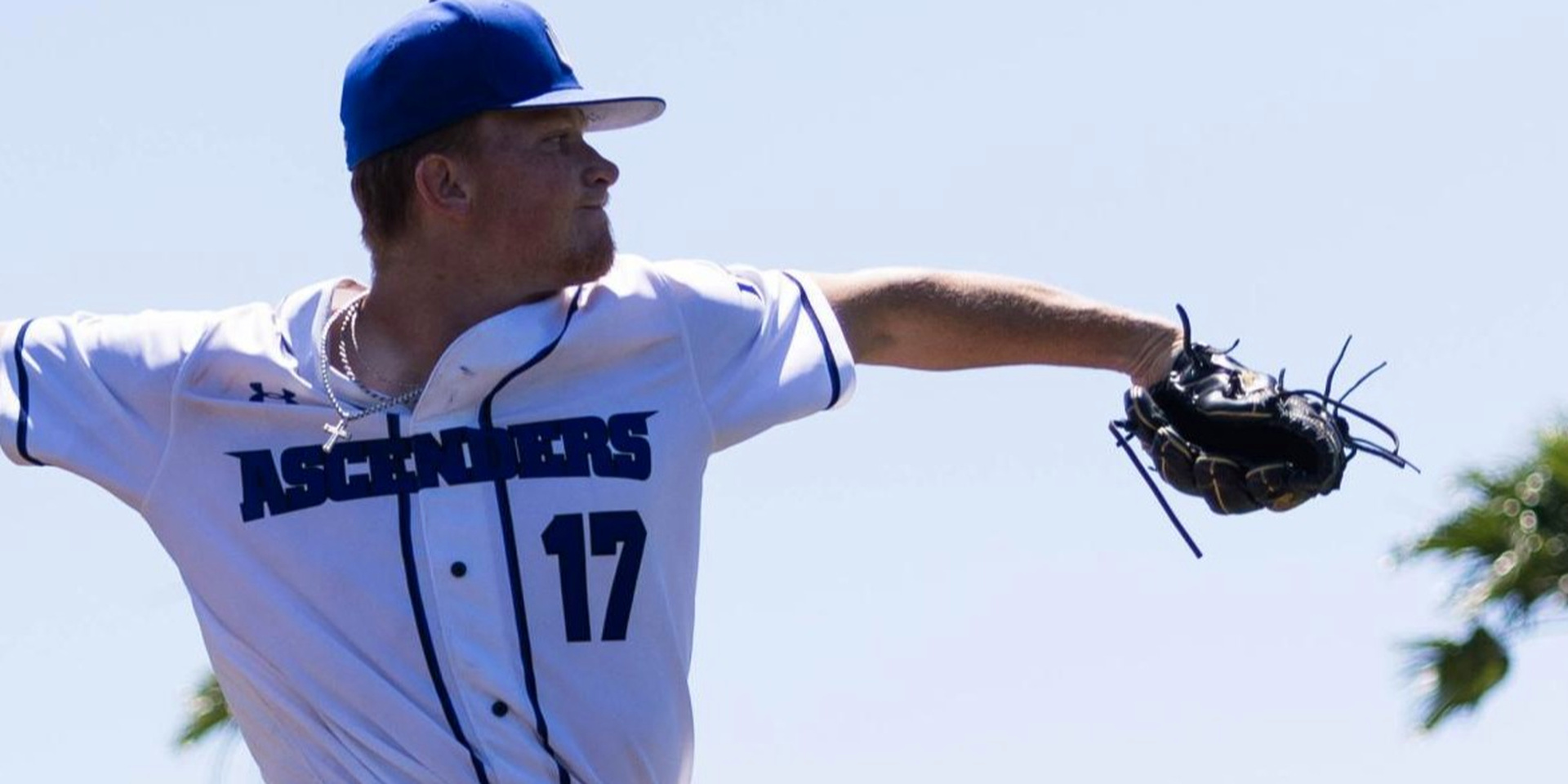 A baseball pitcher extends his gloved arm while preparing to throw.