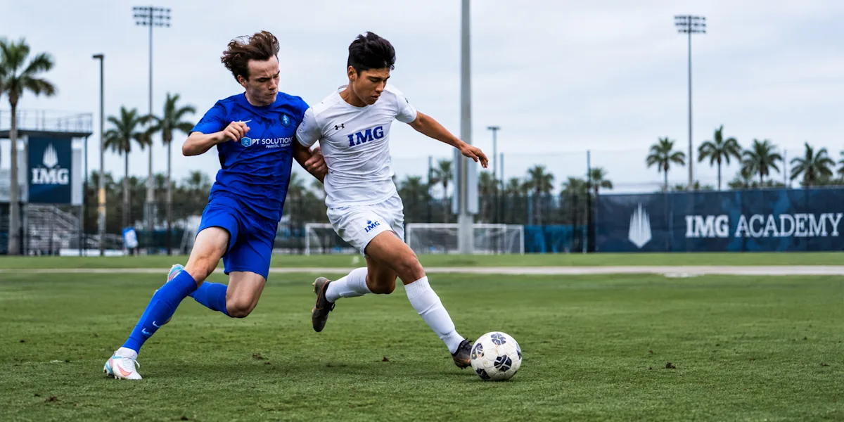 Two soccer players run side by side while competing for the ball.