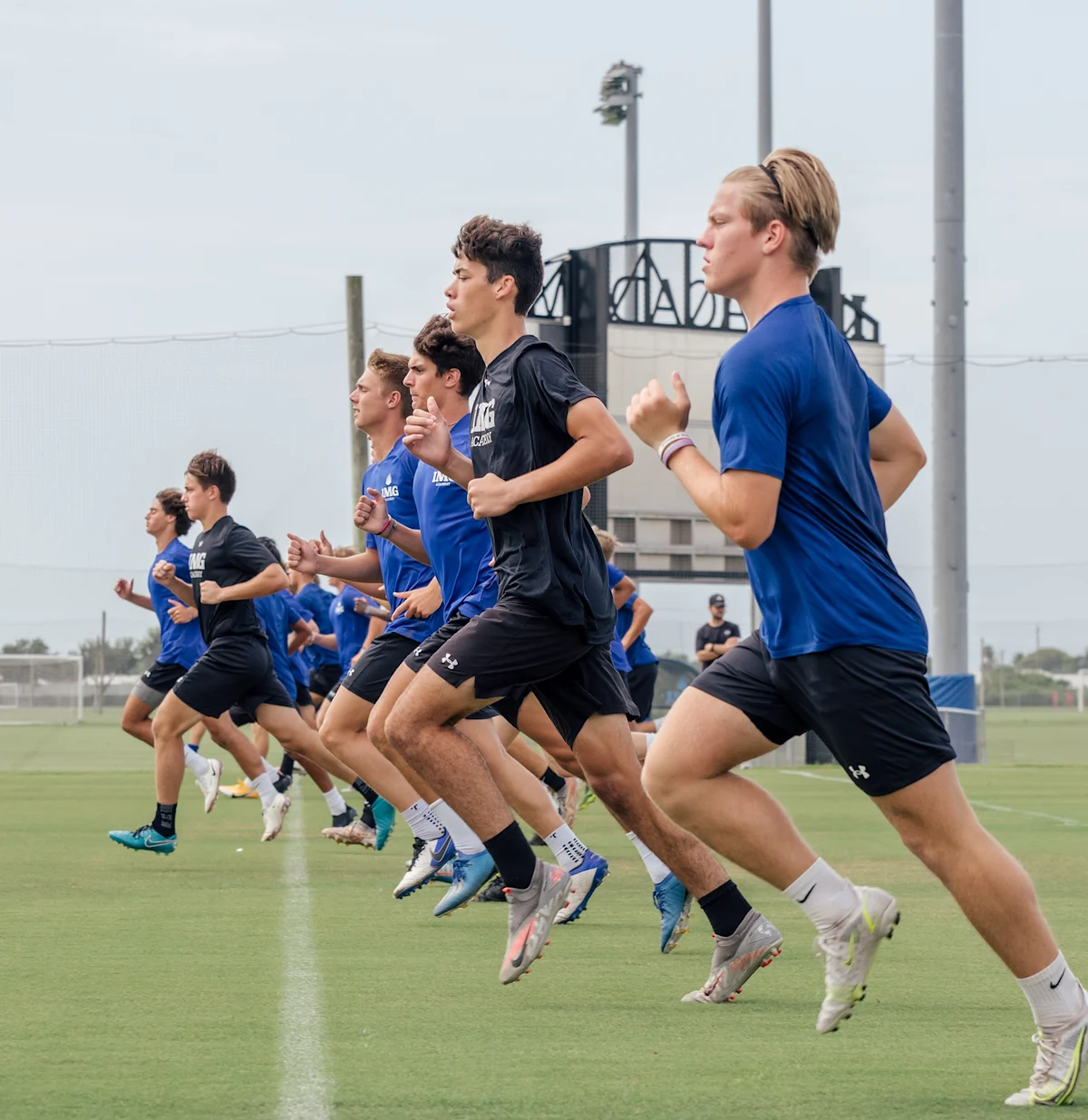 Group of male and female athletes running speed drills.