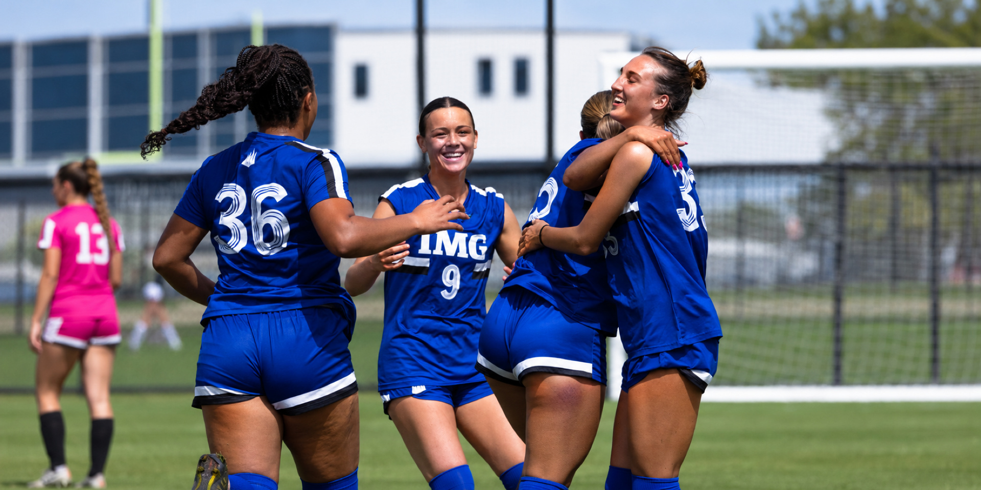 Soccer teammates smile and embrace on the field.