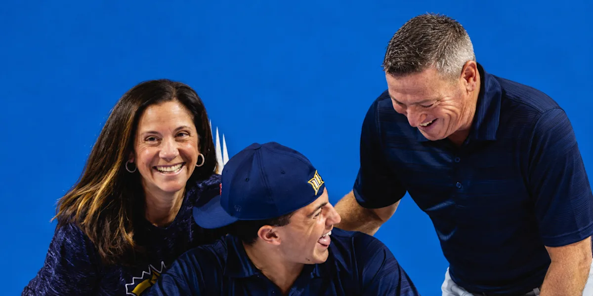 A student-athlete laughs with two adults at a table.