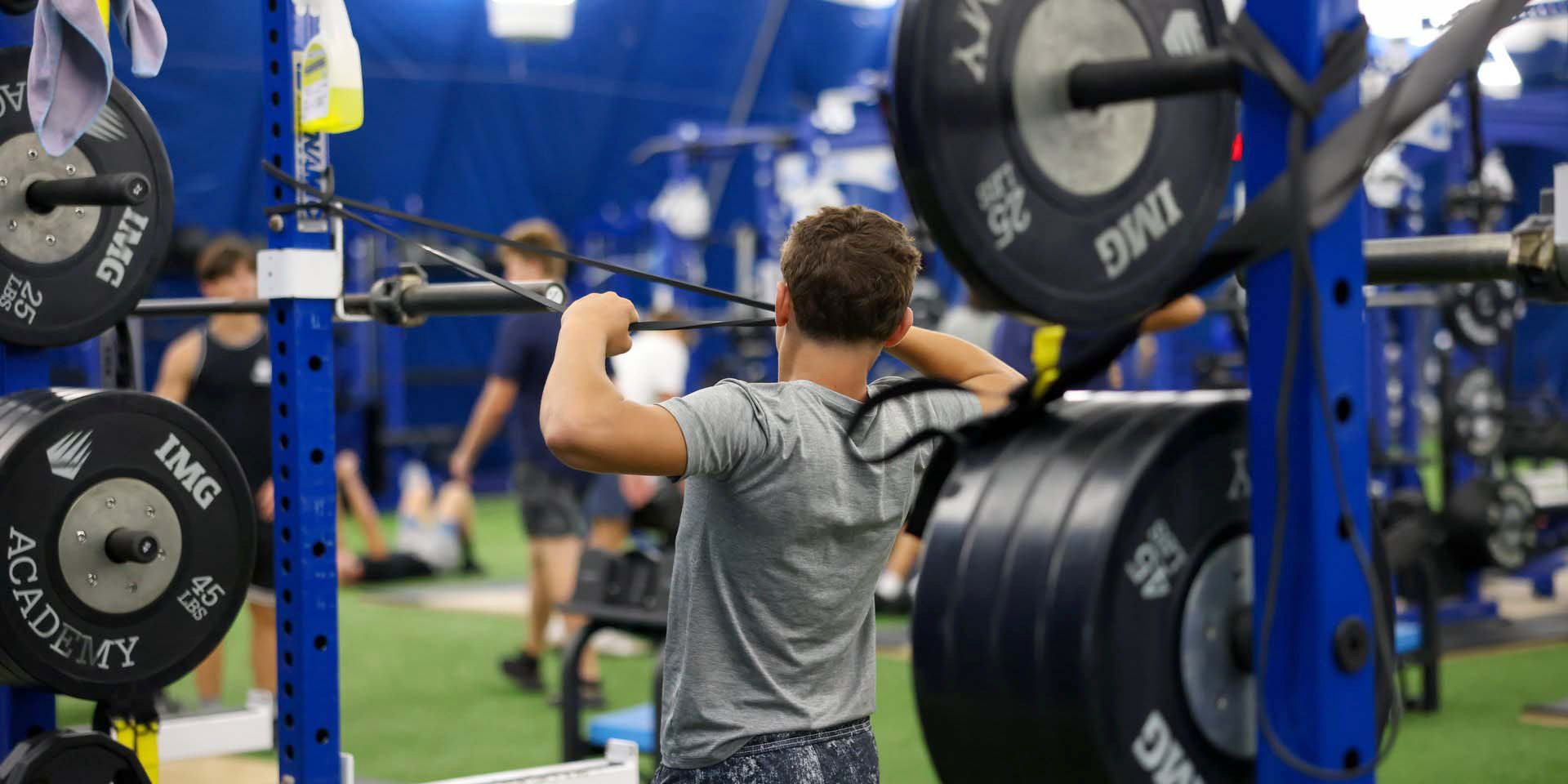 An athlete lifts a barbell in a weight rack.