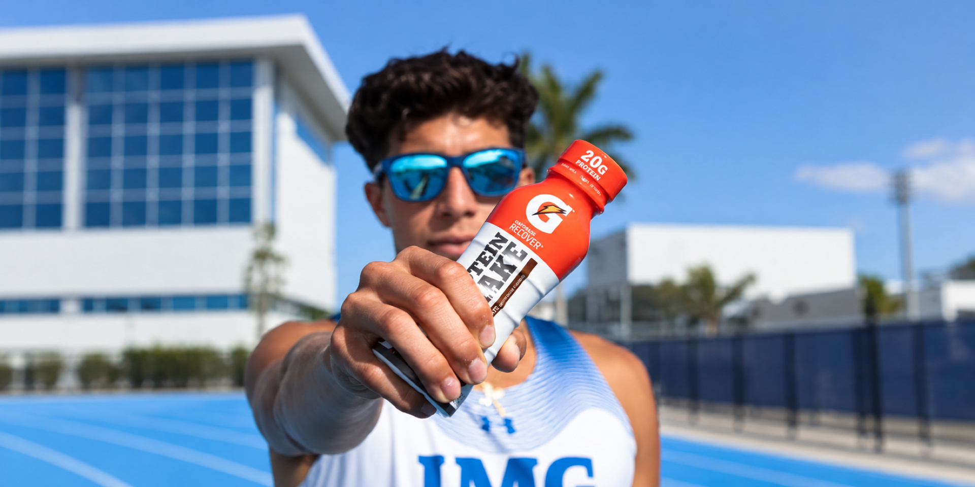 An athlete holds a sports-drink bottle toward the camera.