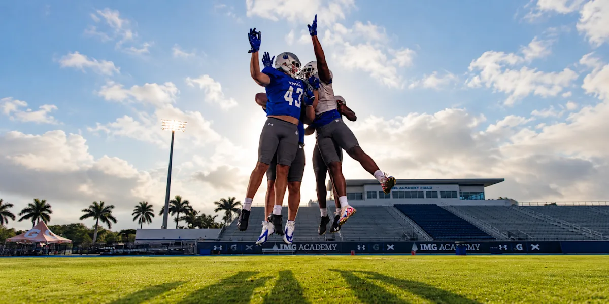 Football players leap to contest a catch on an outdoor field.