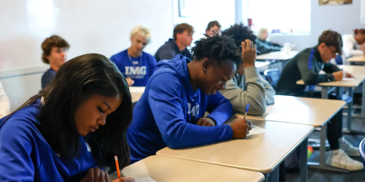Students write at desks during a classroom lesson.