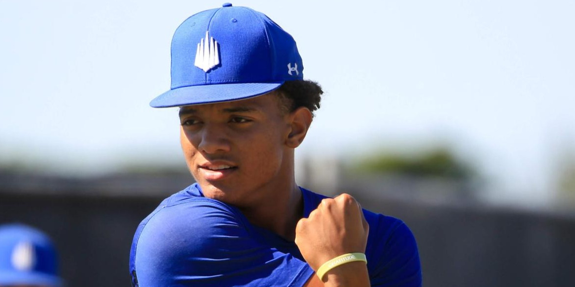A baseball player stretches his shoulder outdoors.