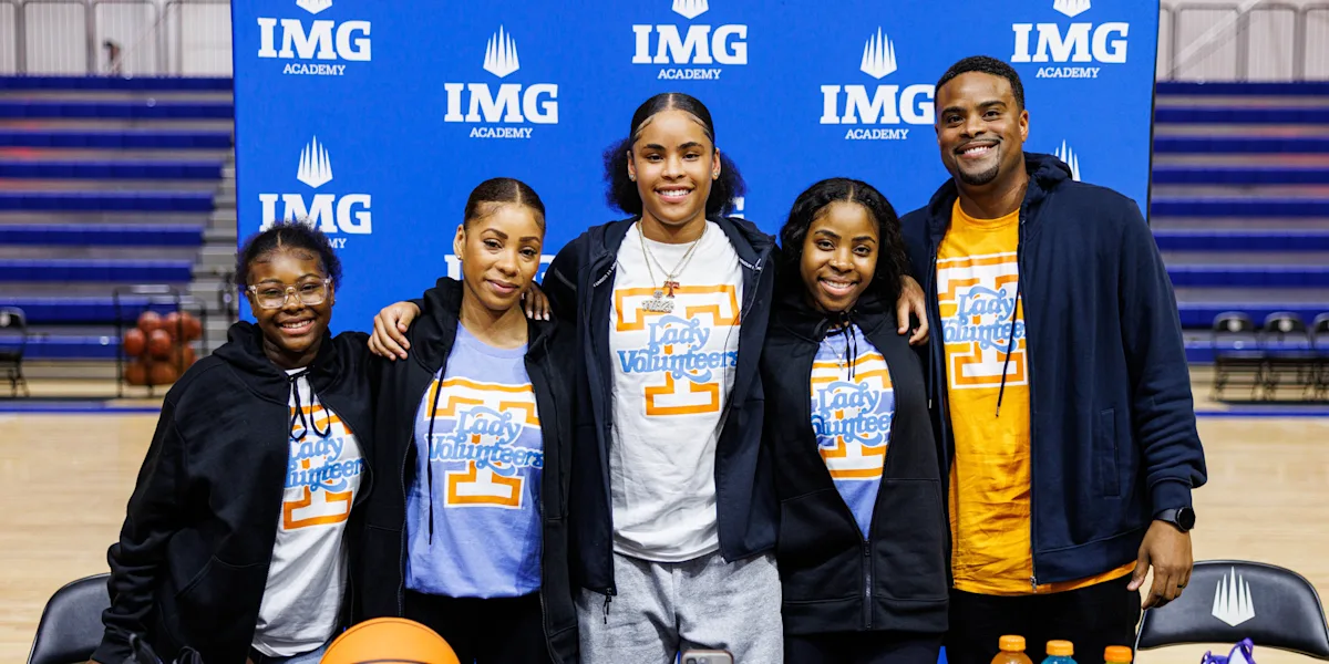 A student-athlete poses with family in front of an IMG Academy backdrop.