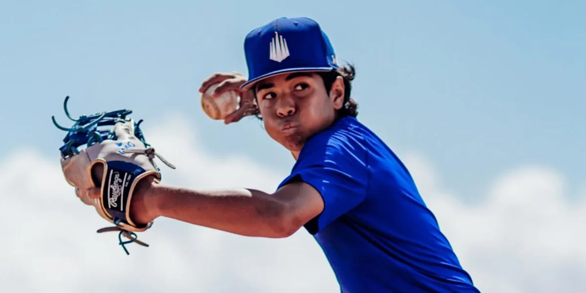 A young baseball player extends his glove while preparing to throw.