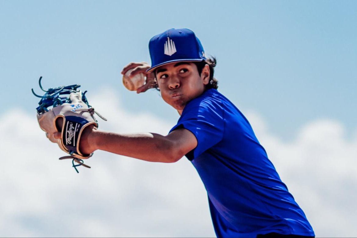 IMG Academy baseball pitcher in a blue uniform throwing a ball during a confidence-building drill.
