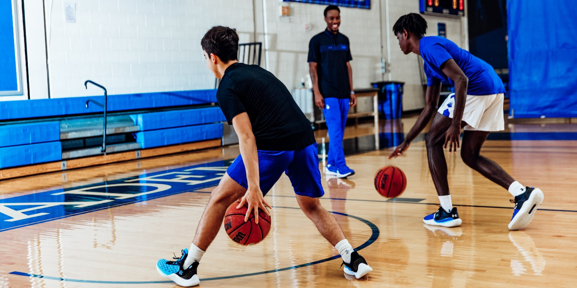 Student-athletes practice basketball dribbling drills with a coach at IMG Academy.