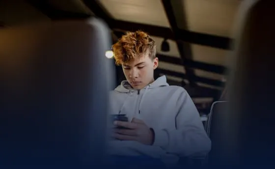 Student athlete on bus engaging with IMG Academy+ Essentials content on his mobile device.