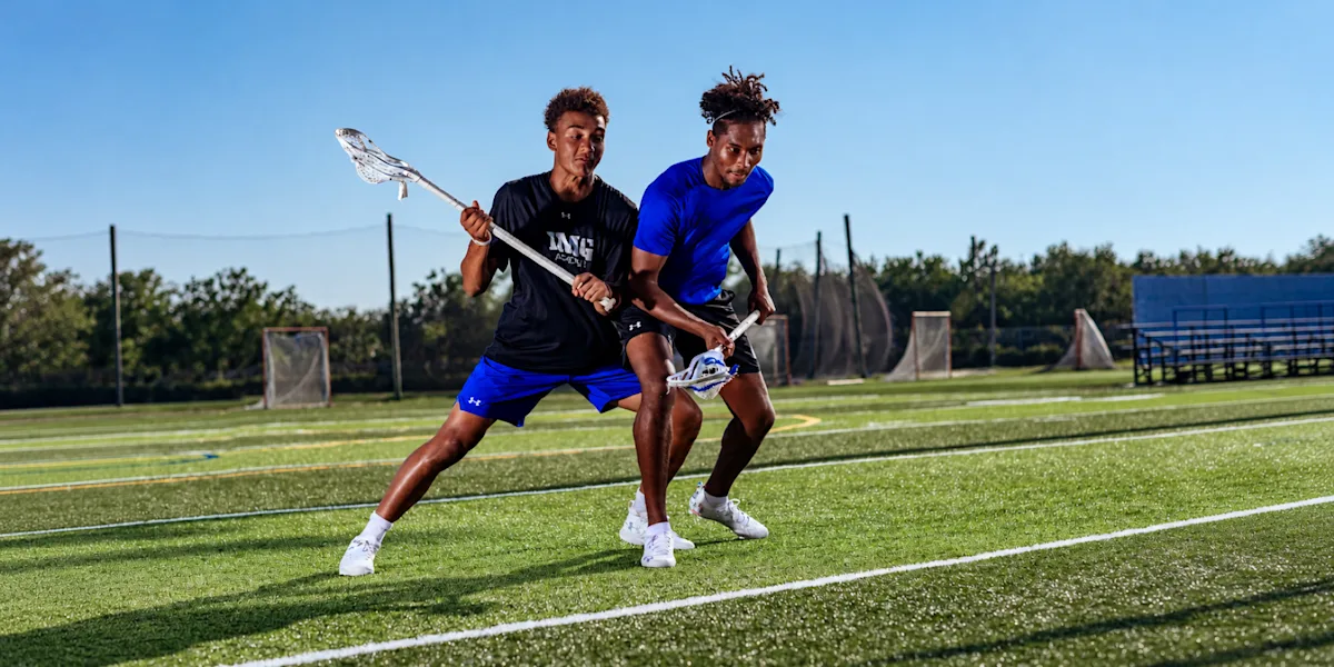 Two lacrosse players compete for position on an outdoor field.