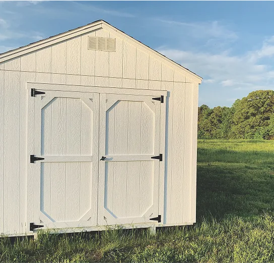 exterior of a shed with white siding in a field