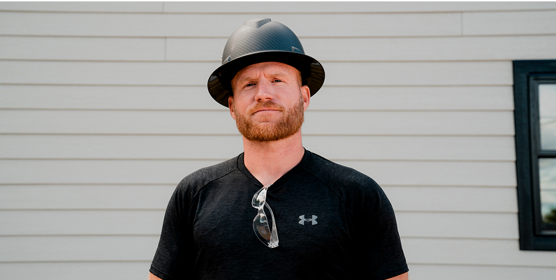kyle stumpenhorst looking at the camera in front of a lap siding wall