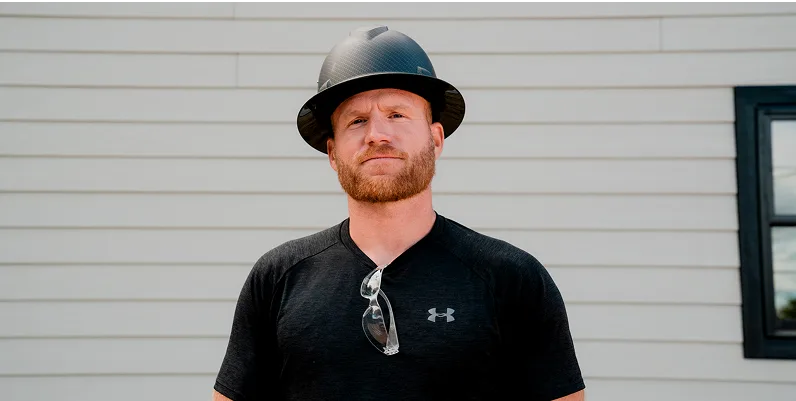 kyle stumpenhorst looking at the camera in front of a lap siding wall