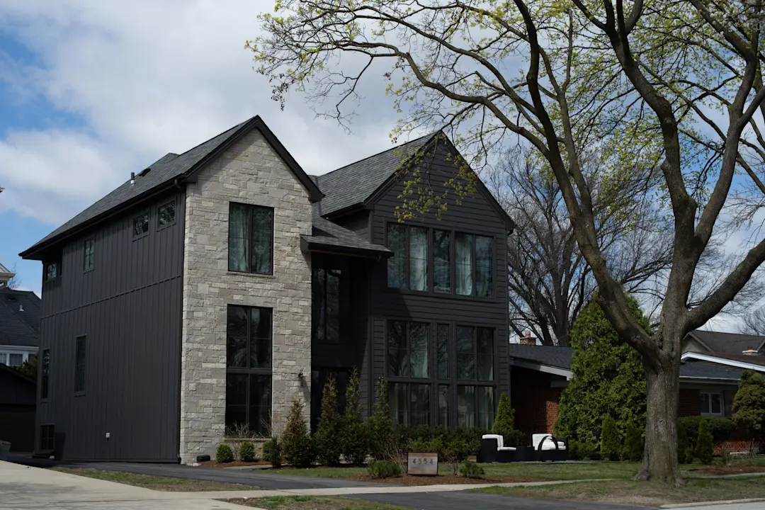 exterior of a two story house with black siding and stone walls