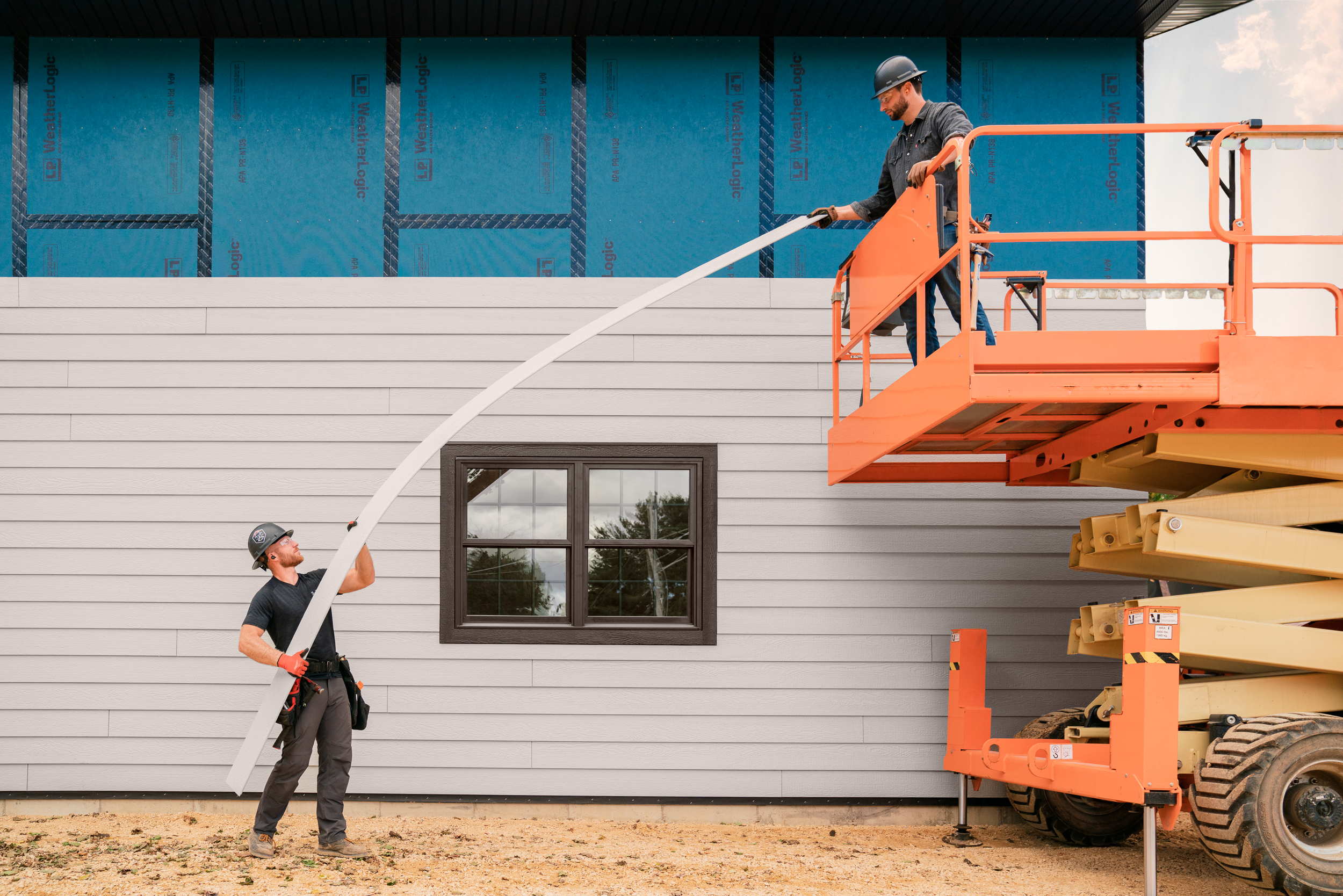 two construction workers holding a piece of siding