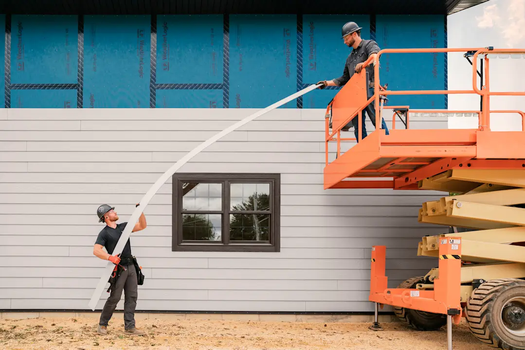 two construction workers holding a piece of siding