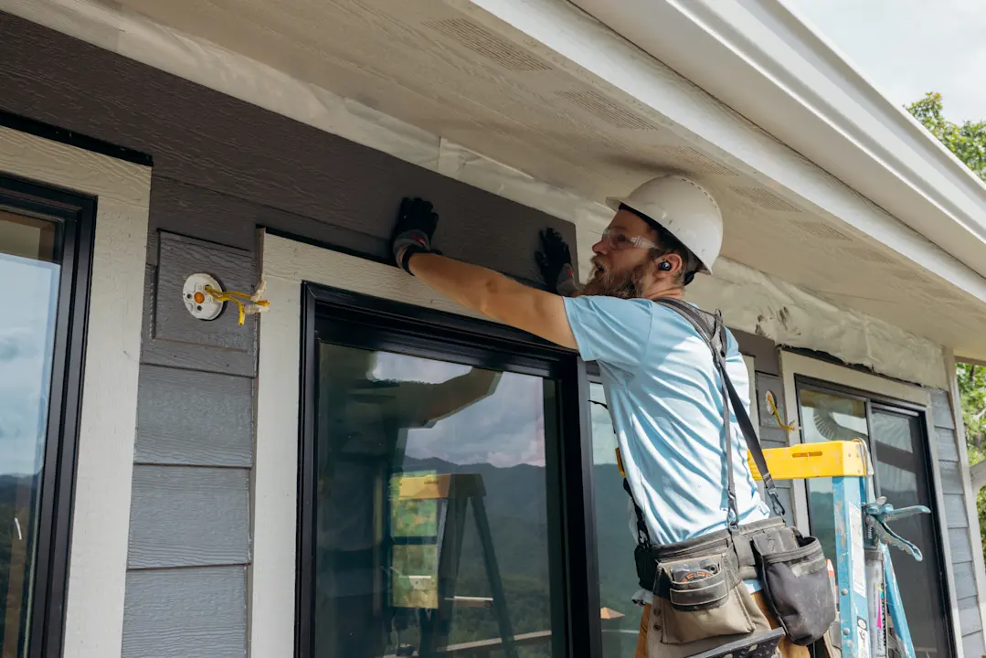 man in hard hat installing siding on a home