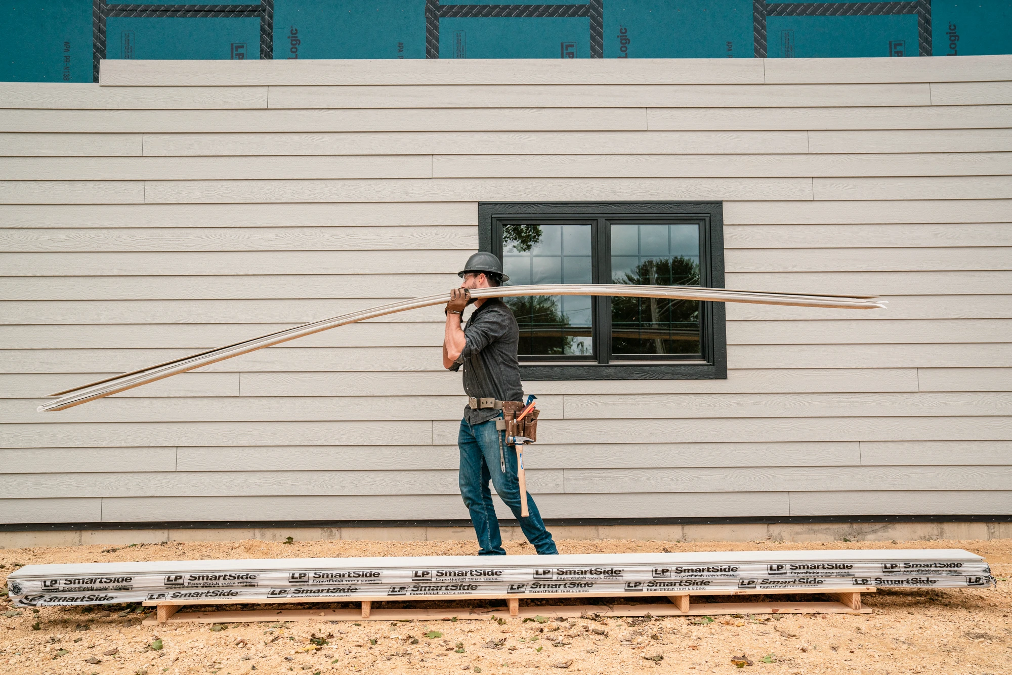 man carrying board in front of window