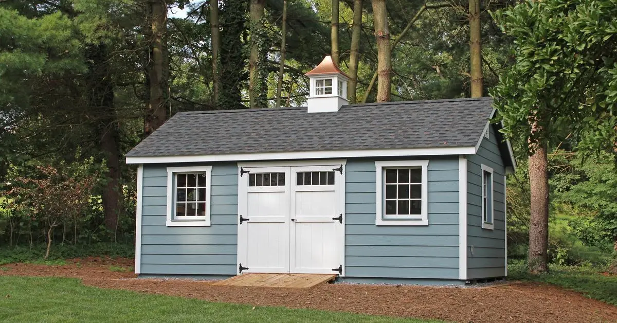 blue shed with white trim in the woods