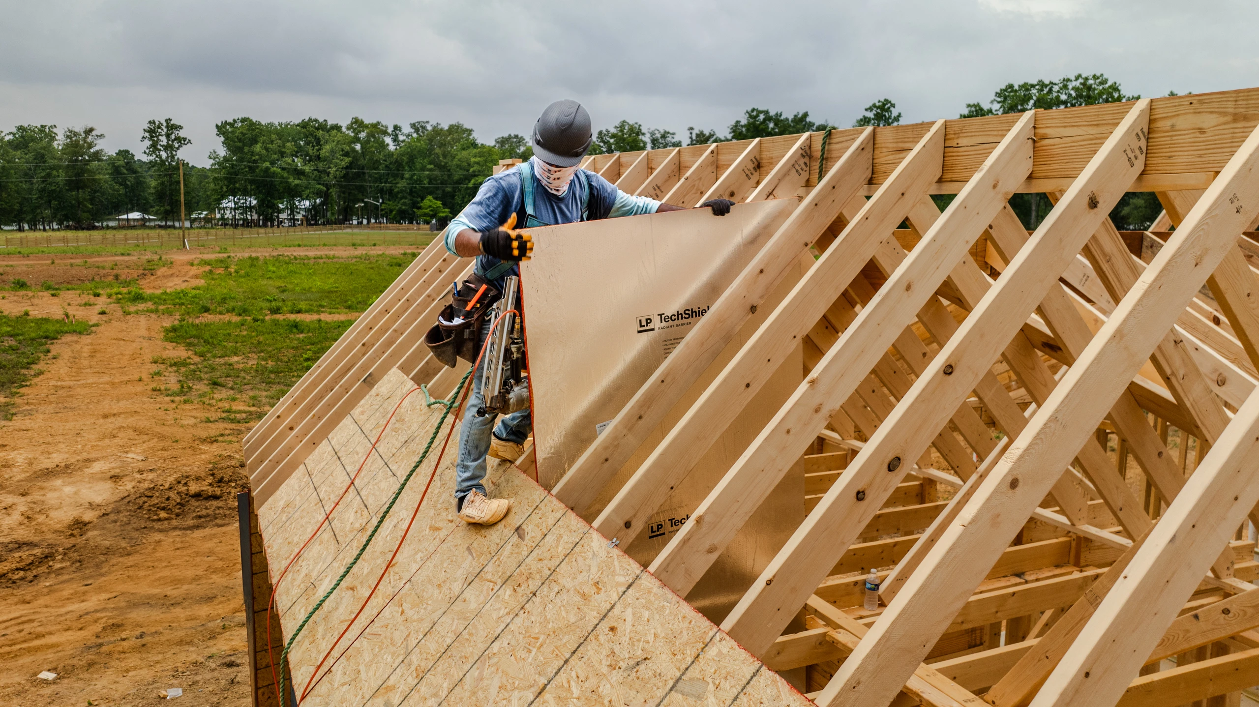Builder holding and installing LP TechShield on a jobsite.