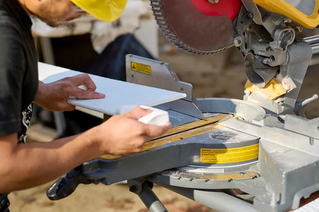 man cutting a piece of siding with a saw